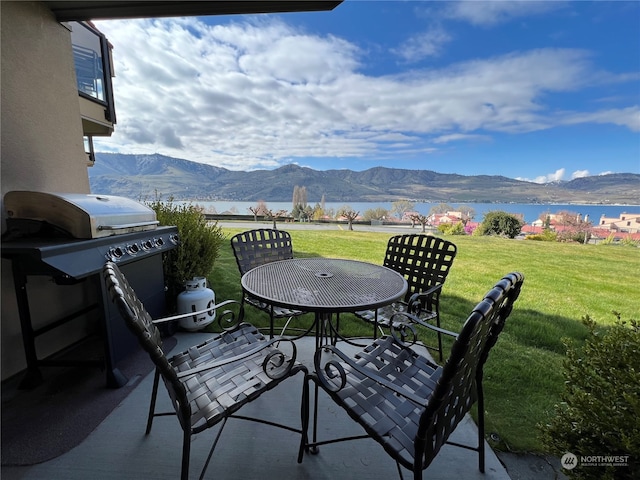 view of patio / terrace with a water and mountain view and a grill