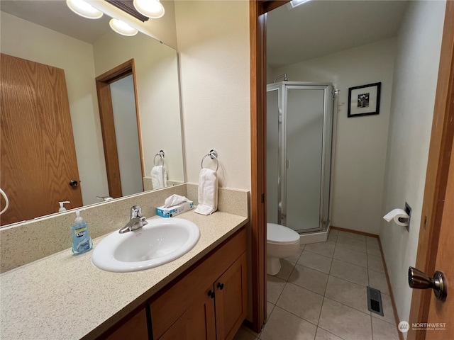 bathroom with a shower with door, vanity, toilet, and tile patterned flooring