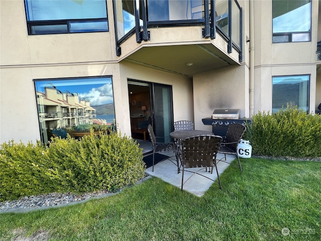 property entrance with a yard, a patio, and a balcony