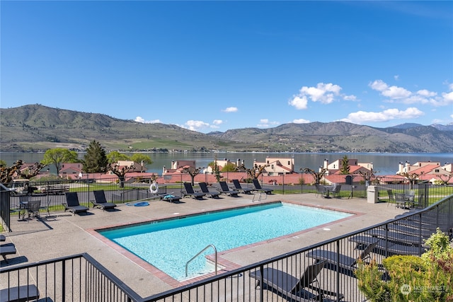 view of swimming pool featuring a water and mountain view and a patio