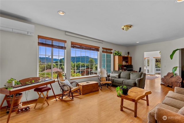 living room with a mountain view, a wall mounted air conditioner, and light hardwood / wood-style floors