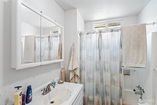 bathroom with a textured ceiling, vanity, and shower / bath combo