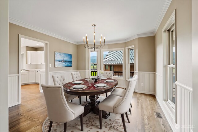 dining area with a chandelier, light wood-type flooring, and ornamental molding