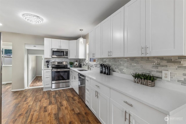 kitchen featuring white cabinets, backsplash, appliances with stainless steel finishes, and a sink