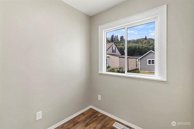 empty room with visible vents, baseboards, and dark wood-style flooring