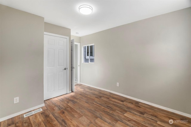 spare room with visible vents, baseboards, and wood finished floors