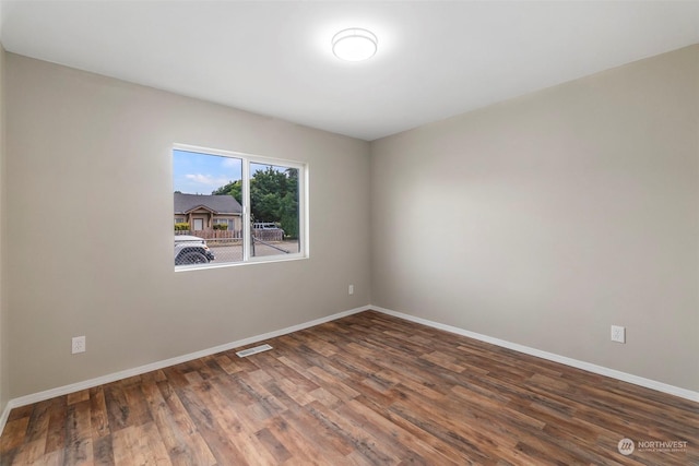 empty room with visible vents, baseboards, and wood finished floors