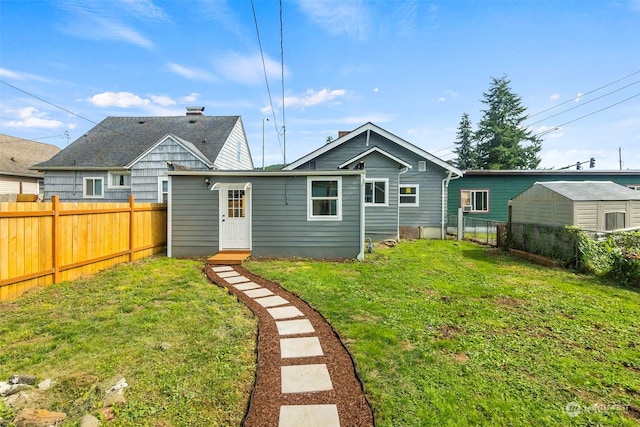 rear view of property featuring a yard and fence