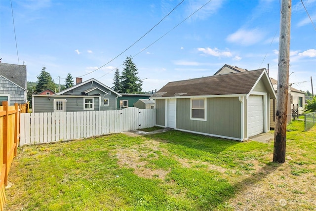 back of house with a gate, fence, driveway, an outdoor structure, and a lawn