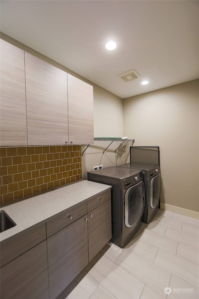 laundry room with washing machine and clothes dryer and cabinets