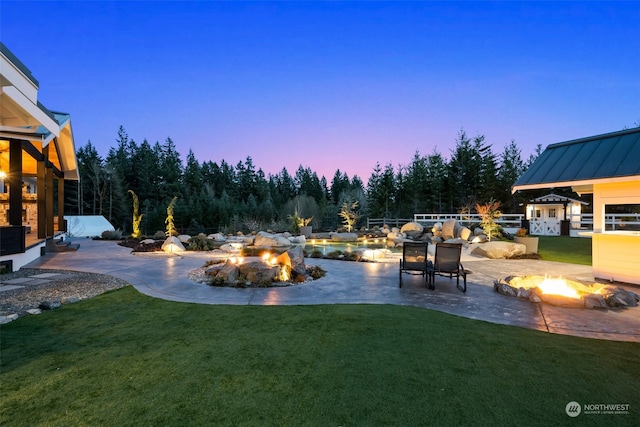 yard at dusk featuring a patio area and an outdoor fire pit