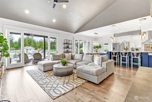 living room with high vaulted ceiling, ceiling fan, and light hardwood / wood-style floors