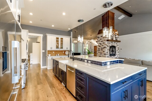 kitchen with pendant lighting, blue cabinetry, high quality appliances, sink, and white cabinets