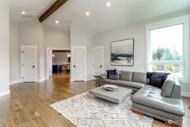 living room with light hardwood / wood-style floors and vaulted ceiling with beams