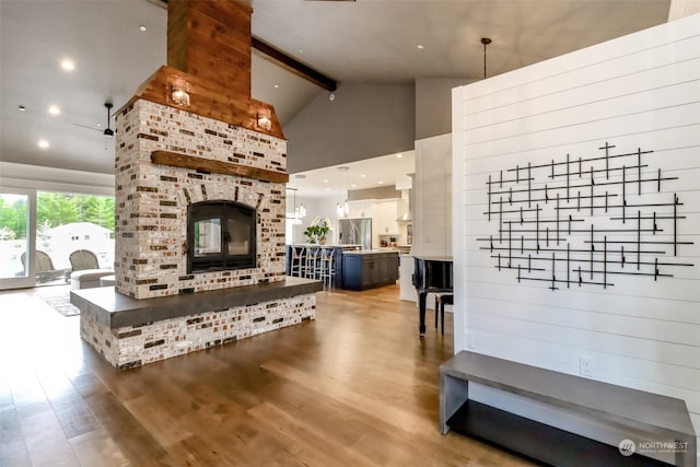 living room with a fireplace, beamed ceiling, high vaulted ceiling, and hardwood / wood-style floors