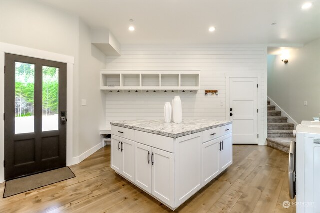 kitchen featuring white cabinetry, light stone counters, a center island, and light hardwood / wood-style floors