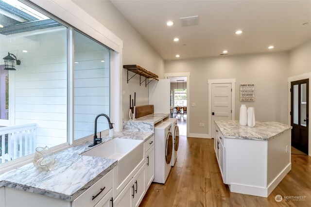 kitchen featuring light hardwood / wood-style flooring, sink, independent washer and dryer, and white cabinets