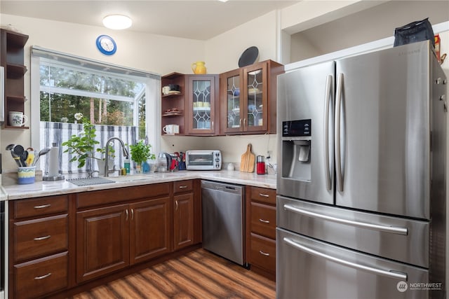 kitchen with dark wood-type flooring, stainless steel appliances, light stone counters, and sink