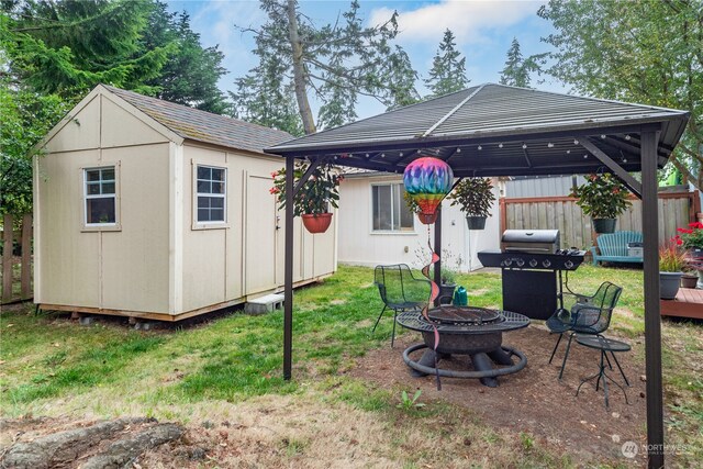 back of property with a lawn, a shed, a gazebo, and an outdoor fire pit