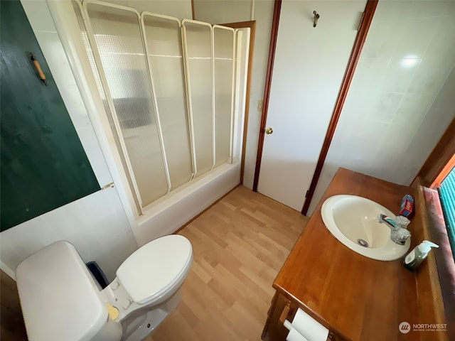 bathroom with hardwood / wood-style floors, toilet, a shower with door, and vanity