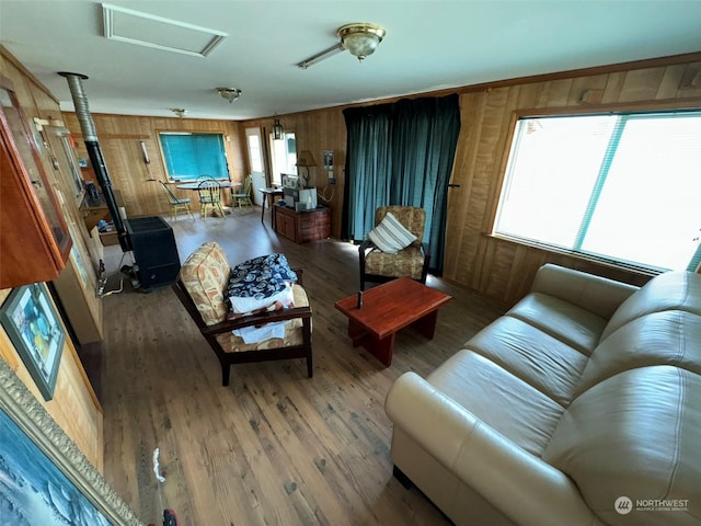 living room featuring wooden walls, a wood stove, attic access, and wood finished floors