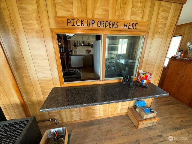 room details featuring wooden walls, freestanding refrigerator, and wood finished floors