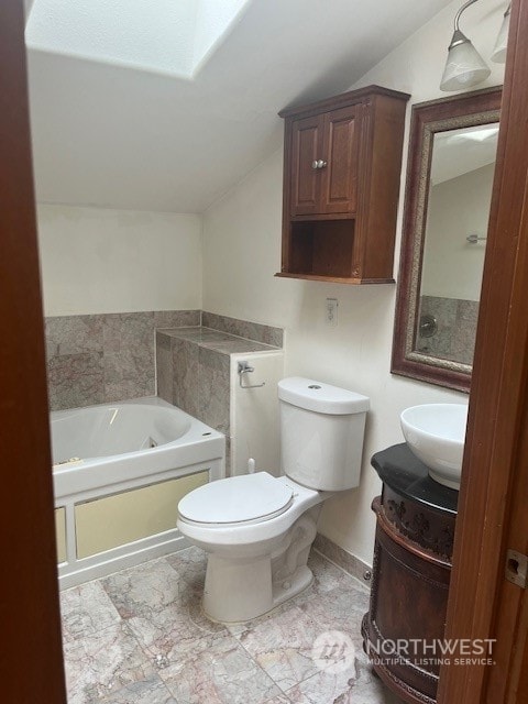 bathroom featuring a tub to relax in, vanity, toilet, and lofted ceiling