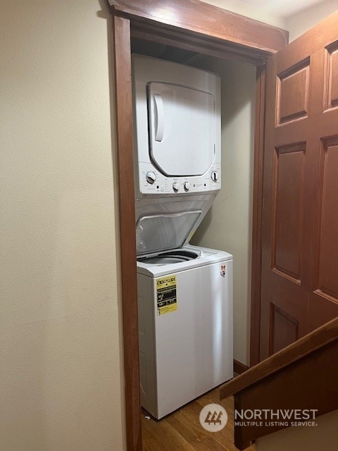 clothes washing area featuring hardwood / wood-style flooring and stacked washer / drying machine