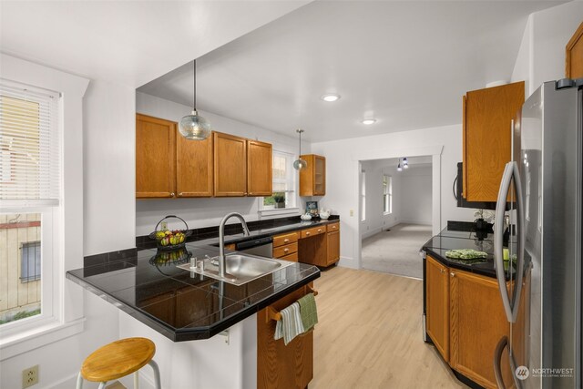 kitchen featuring a breakfast bar area, stainless steel fridge, pendant lighting, light hardwood / wood-style flooring, and kitchen peninsula