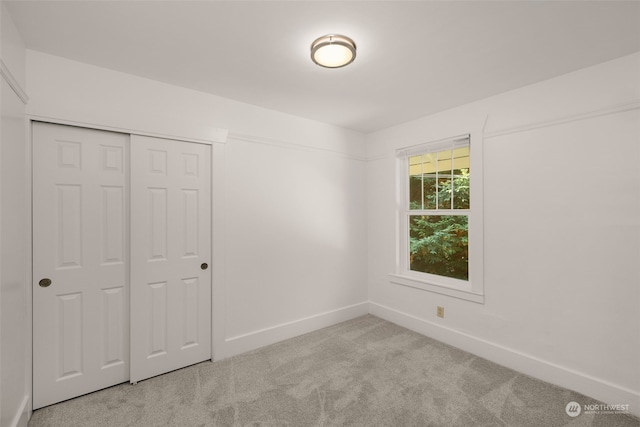 unfurnished bedroom with light colored carpet and a closet