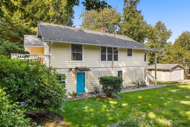 rear view of house featuring an outdoor structure, a garage, and a yard