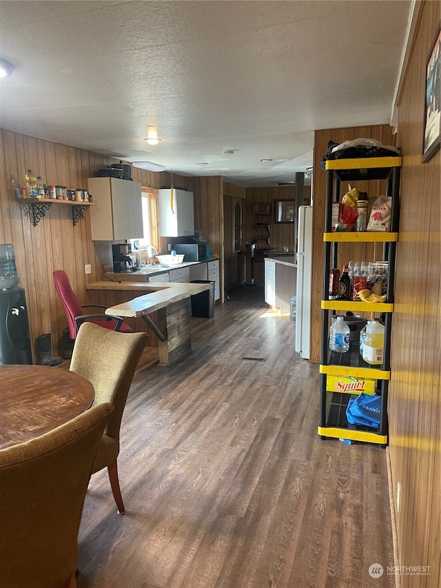 interior space with a textured ceiling, wood walls, and hardwood / wood-style flooring