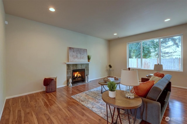 living room with wood-type flooring and a tiled fireplace