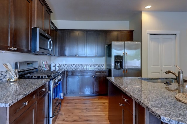 kitchen featuring stone countertops, stainless steel appliances, sink, and light hardwood / wood-style floors