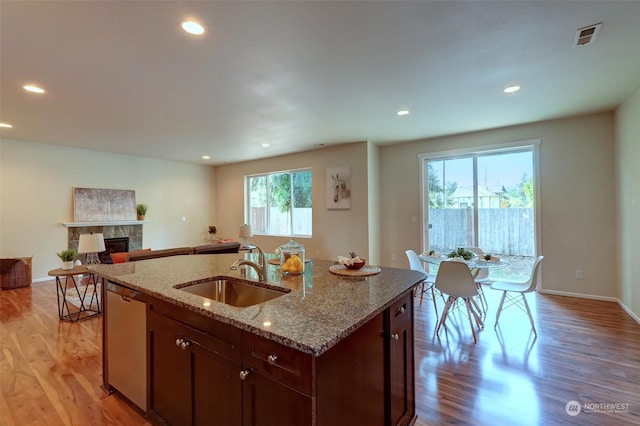 kitchen featuring plenty of natural light, dishwasher, a tiled fireplace, and sink