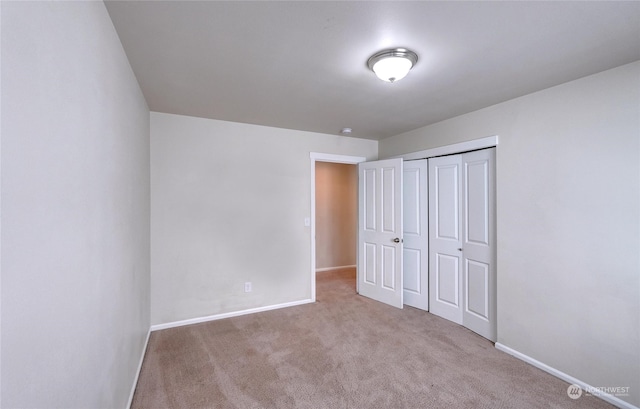 unfurnished bedroom with light colored carpet and a closet