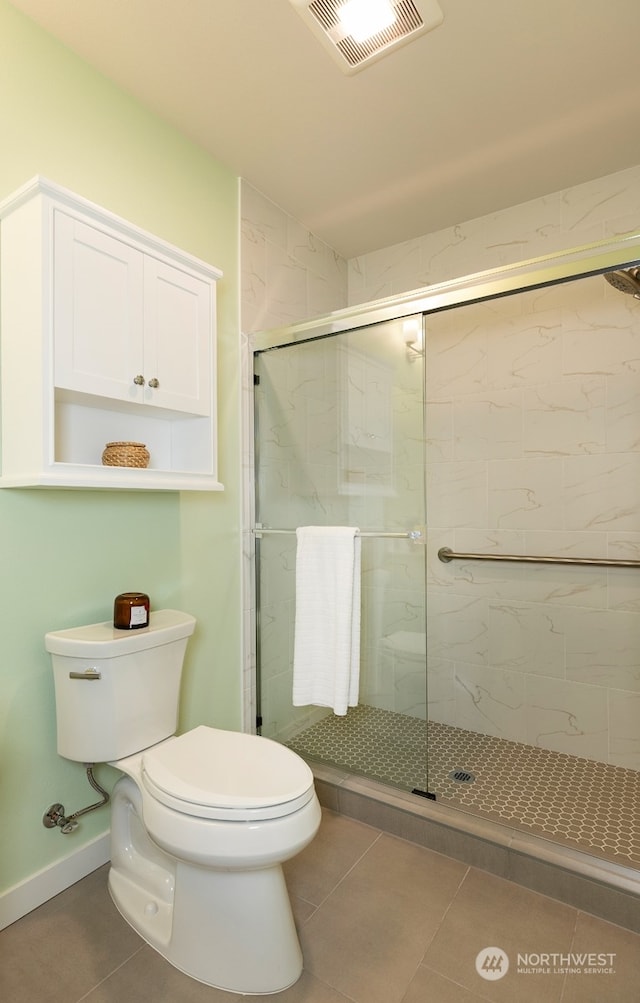 bathroom with a shower with door, tile patterned floors, and toilet