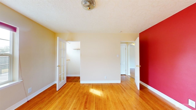 unfurnished bedroom with light hardwood / wood-style floors, multiple windows, and a textured ceiling