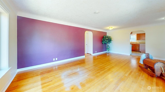 unfurnished living room with a textured ceiling and light hardwood / wood-style flooring