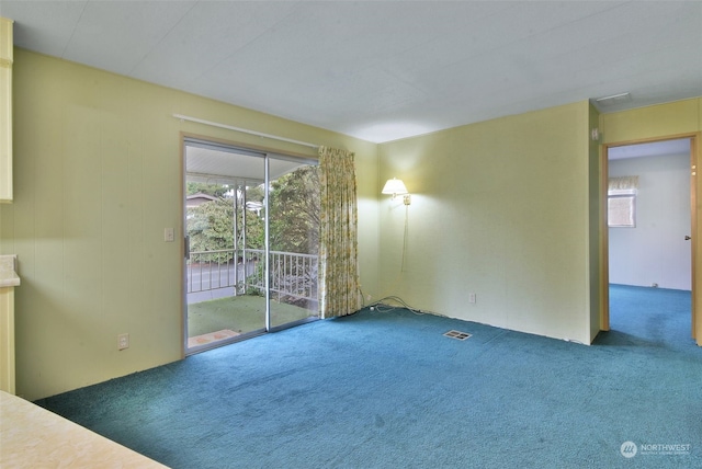 spare room with a wealth of natural light and dark carpet