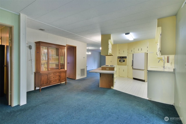 kitchen with a breakfast bar area, sink, white appliances, and carpet floors