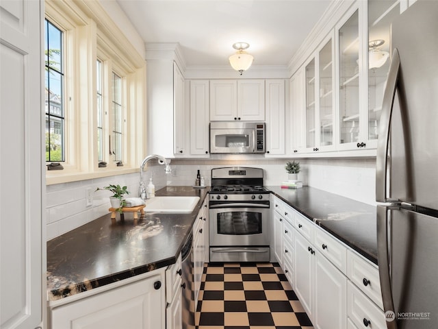 kitchen with appliances with stainless steel finishes, white cabinetry, sink, and tasteful backsplash