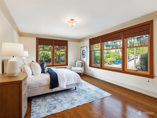 bedroom with dark wood-type flooring, ornamental molding, and multiple windows