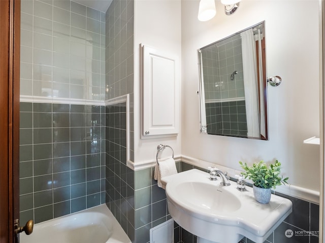 bathroom featuring tile walls, tiled shower / bath combo, and sink