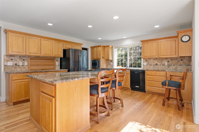 kitchen featuring dishwasher, stainless steel fridge, a center island, and light wood-type flooring