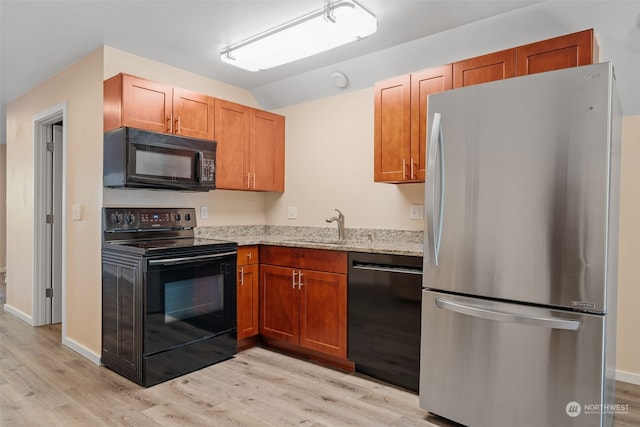 kitchen featuring sink, light stone counters, light hardwood / wood-style floors, vaulted ceiling, and black appliances