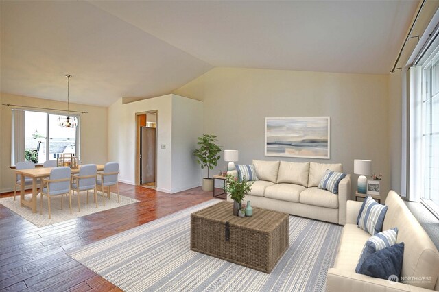 living room featuring vaulted ceiling, a chandelier, and hardwood / wood-style flooring