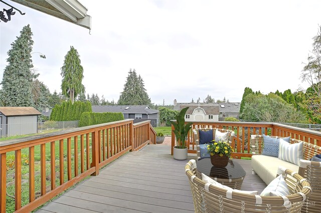 wooden deck with a shed, a lawn, and outdoor lounge area