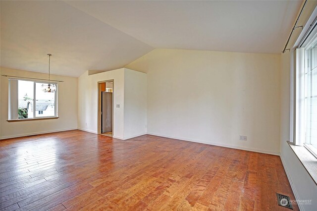 spare room featuring light hardwood / wood-style flooring, lofted ceiling, and an inviting chandelier