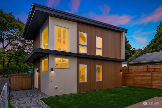 back house at dusk featuring a yard